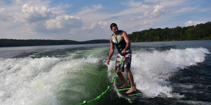 wakesurfer riding doomswell board and holding rope