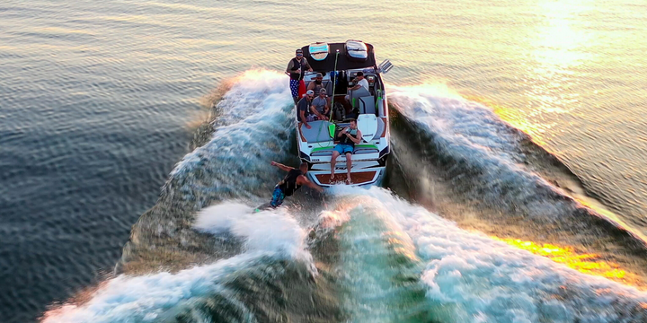 boat towing wakesurfer at sunset