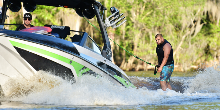 man holding rope wakesurfing behind boat