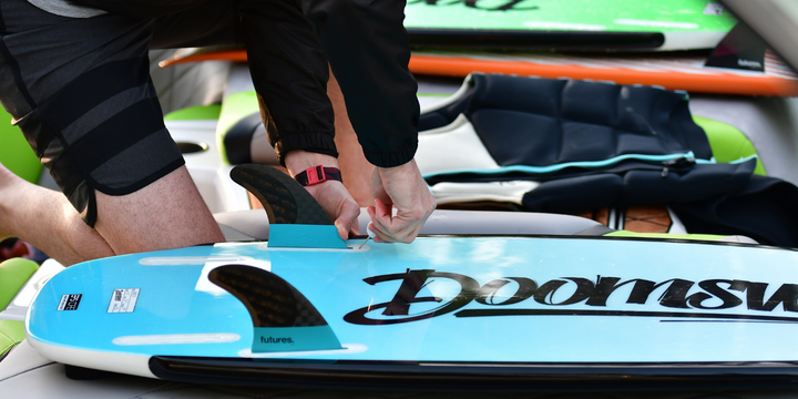guy inserting fins into doomswell wakesurf board